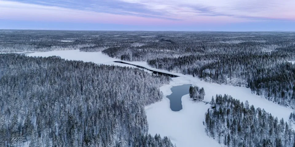 Talvinen ilmapanoraama Oulangan lumisesta joesta ja metsästä.